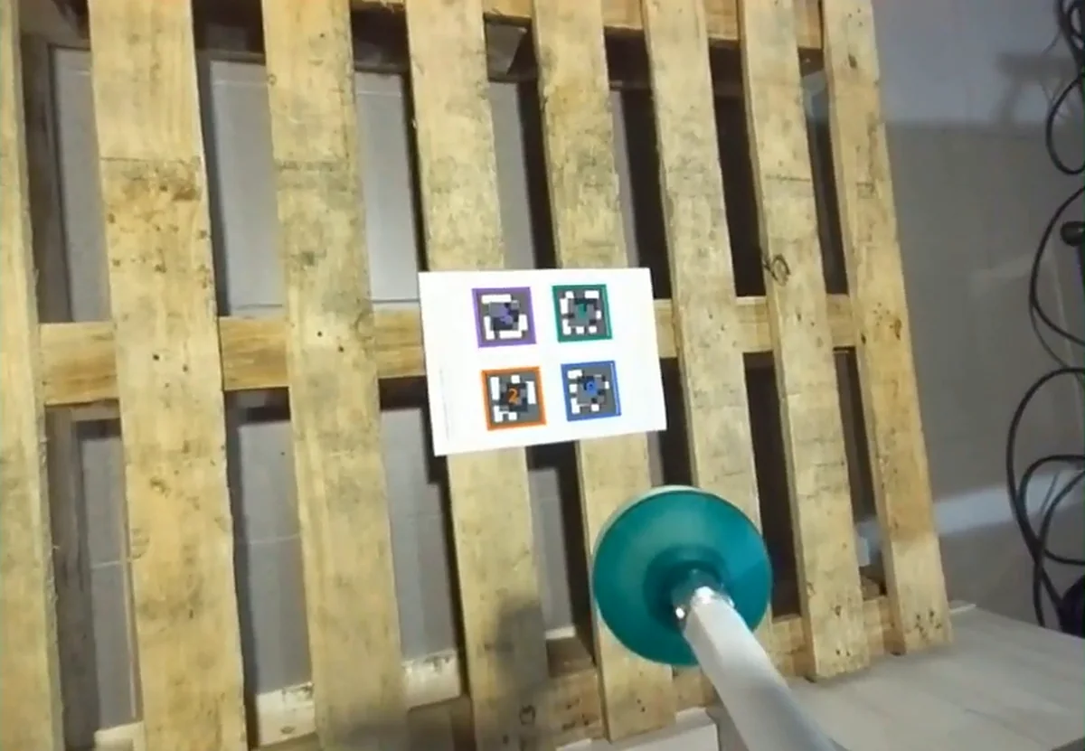 ThRiVer's camera view during calibration, with all four fiducial tags on the printed board outlined by the detector as the suction tool approaches.
